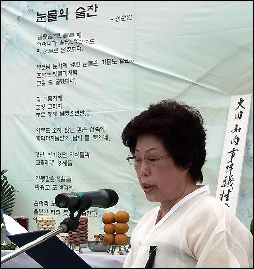 산내학살지에서 오빠를 잃었다는 신순란 유족이 헌시를 낭송하고 있다. 신씨의 뒤로 무대중앙에 내걸린 천에 신씨의 헌시 '눈물의 술잔'이 보인다. 